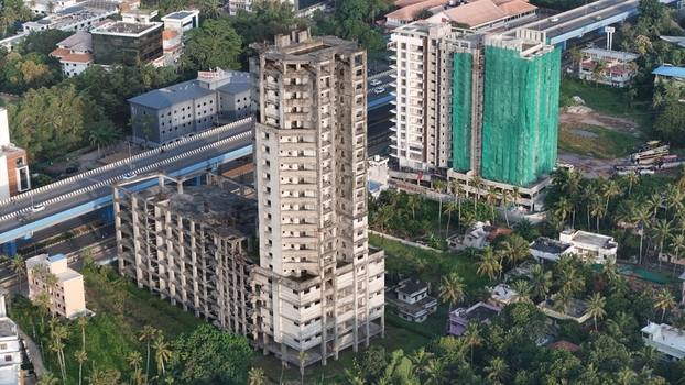 Aerial view of the unfinished concrete structure of a high rise building in Kazhakuttam surrounded by lush greenery nearby residential buildings and a highway flyover in Thiruvananthapuram Kerala India. Aerial view of the unfinished concrete structure of a high rise building in Kazhakuttam surrounded by lush greenery nearby residential buildings and a highway flyover in Thiruvananthapuram Kerala India.