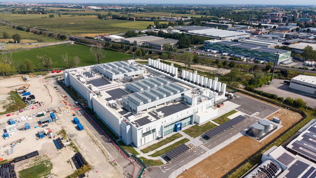 Aerial view of a modern data center campus with advanced digital infrastructure rooftop solar panels and surrounding industrial landscape in Melegnano Lombardy Italy.