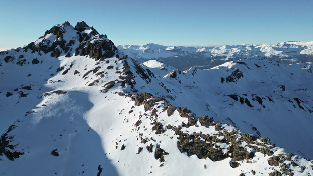 Aerial view of snow covered Becs de Bosson peak where rocky formations meet the pristine white expanse under a clear blue sky Anniviers Valais Switzerland. Aerial view of snow covered Becs de Bosson peak where rocky formations meet the pristine white expanse under a clear blue sky Anniviers Valais Switzerland.