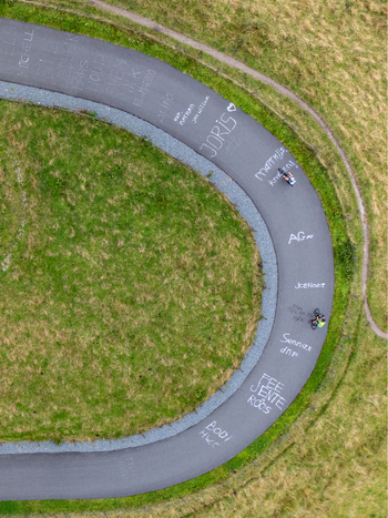 Aerial view of cyclists riding on the winding dark asphalt of Col du Vam with the vibrant green grass adding a striking contrast Col du Vam Drenthe Netherlands.