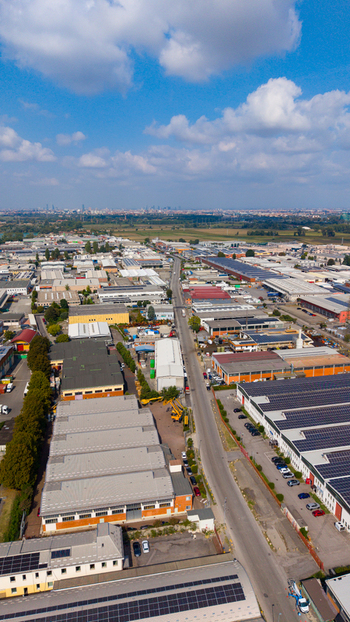 Aerial view of an industrial zone with warehouses factory buildings solar panels on rooftops and a road running through the area in Milan Lombardy Italy. Aerial view of an industrial zone with warehouses factory buildings solar panels on rooftops and a road running through the area in Milan Lombardy Italy.