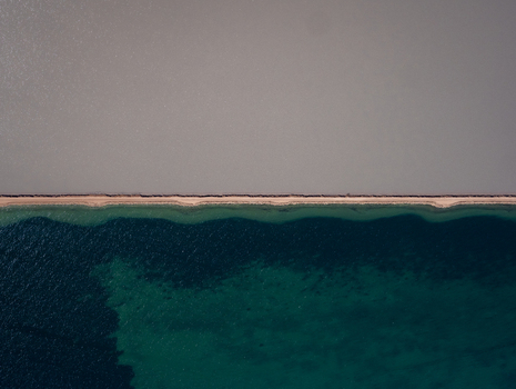 Aerial view of the salt lake division showing contrasting deep blue water and light grey salt flats separated by a narrow sandy causeway in Kalbarri Western Australia Australia. Aerial view of the salt lake division showing contrasting deep blue water and light grey salt flats separated by a narrow sandy causeway in Kalbarri Western Australia Australia.
