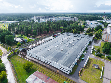 Olaine parish Latvia 04 July 2026 Aerial view of a large industrial warehouse complex with a flat roof surrounded by green trees and railway infrastructure in Olaine Municipality Latvia. Olaine parish Latvia 04 July 2026 Aerial view of a large industrial warehouse complex with a flat roof surrounded by green trees and railway infrastructure in Olaine Municipality Latvia.