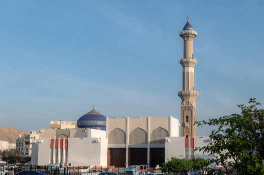View of a mosque with a tall minaret and a blue dome under a clear blue sky in Muscat Muscat Governorate Oman. View of a mosque with a tall minaret and a blue dome under a clear blue sky in Muscat Muscat Governorate Oman.