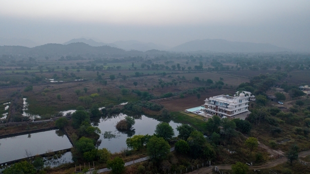 Aerial view of a white villa with a swimming pool situated near a pond in the rural landscape of Jodhpur Rajasthan India. Aerial view of a white villa with a swimming pool situated near a pond in the rural landscape of Jodhpur Rajasthan India.
