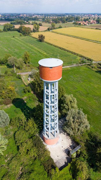 Aerial view of the water tower surrounded by green fields and trees in Mediglia Lombardy Italy.