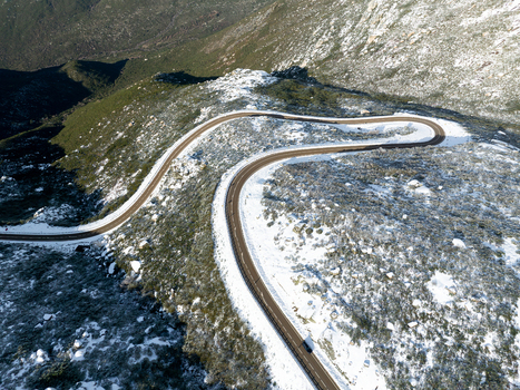 Aerial view of a winding road cutting through a snow dusted mountain landscape with shadows dancing across the terrain São Romão Guarda District Portugal. Aerial view of a winding road cutting through a snow dusted mountain landscape with shadows dancing across the terrain São Romão Guarda District Portugal.