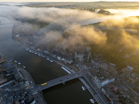 Aerial view of the Collegiate Church of Our Lady of Dinant and the Meuse River at sunrise with mist rolling over the historic town in Dinant Wallonia Belgium. Aerial view of the Collegiate Church of Our Lady of Dinant and the Meuse River at sunrise with mist rolling over the historic town in Dinant Wallonia Belgium.