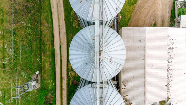 Aerial view of silver silos standing tall against a backdrop of green fields and beige pathways creating a striking contrast of industrial and natural elements Sremska Mitrovica Vojvodina Serbia. Aerial view of silver silos standing tall against a backdrop of green fields and beige pathways creating a striking contrast of industrial and natural elements Sremska Mitrovica Vojvodina Serbia.