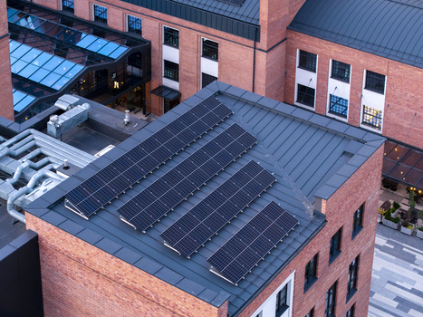 Aerial view of solar panels installed on the metal roof of a modern red brick building in Poland. Aerial view of solar panels installed on the metal roof of a modern red brick building in Poland.