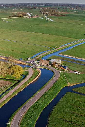 Aerial view of the wipbrug drawbridge and a traditional house next to a winding canal and green fields in Spanbroek North Holland Netherlands.