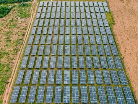 Aerial view of a large solar farm with rows of photovoltaic panels installed in a rural landscape in Ogun State Nigeria.