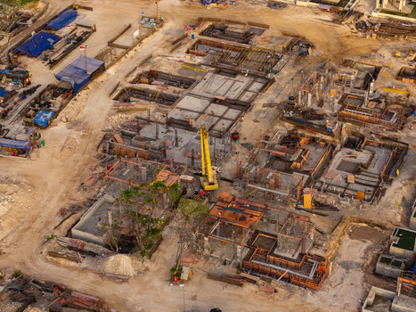 Aerial view of a resort development construction site with concrete foundations steel reinforcements and a yellow crane in Kecamatan Kuta Selatan Bali Indonesia. Aerial view of a resort development construction site with concrete foundations steel reinforcements and a yellow crane in Kecamatan Kuta Selatan Bali Indonesia.