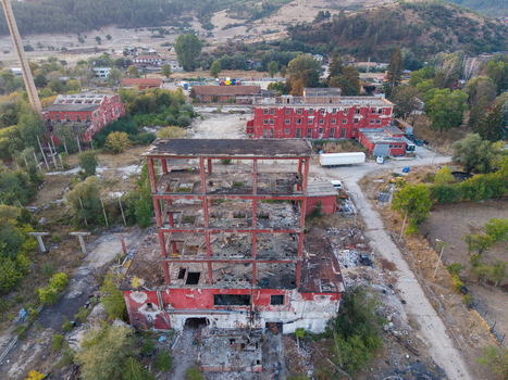 Aerial view of an abandoned industrial complex featuring red brick buildings a tall chimney and a central ruined structure with exposed steel framework in Velingrad Pazardzhik Bulgaria. Aerial view of an abandoned industrial complex featuring red brick buildings a tall chimney and a central ruined structure with exposed steel framework in Velingrad Pazardzhik Bulgaria.