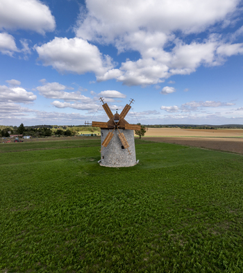 Aerial view of the historic Regi Szelmalom windmill standing in a green field under a blue sky with clouds in Tes Hungary. Aerial view of the historic Regi Szelmalom windmill standing in a green field under a blue sky with clouds in Tes Hungary.