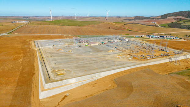 Aerial view of an electrical substation and wind farm surrounded by rolling hills and brown fields under a clear blue sky Swellendam Western Cape South Africa. Aerial view of an electrical substation and wind farm surrounded by rolling hills and brown fields under a clear blue sky Swellendam Western Cape South Africa.