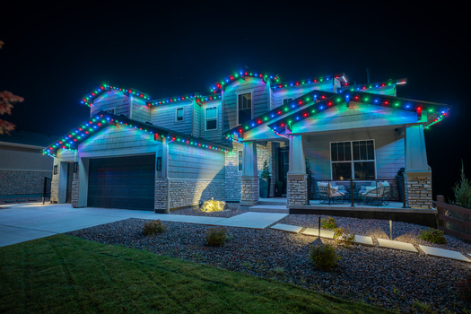 View of a suburban house at night illuminated with colorful LED roofline lights featuring stone and siding architecture with a front porch in Aurora Colorado United States. View of a suburban house at night illuminated with colorful LED roofline lights featuring stone and siding architecture with a front porch in Aurora Colorado United States.