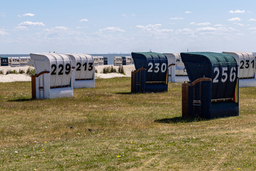 View of numbered beach chairs on the grassy dunes of Strand Schillig under a clear blue sky in Wangerland Niedersachsen Germany. View of numbered beach chairs on the grassy dunes of Strand Schillig under a clear blue sky in Wangerland Niedersachsen Germany.