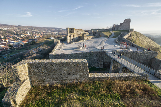 View of the historic Devin Castle ruins with stone walls a pedestrian bridge and visitors under a clear blue sky in Bratislava IV Bratislava Region Slovakia. View of the historic Devin Castle ruins with stone walls a pedestrian bridge and visitors under a clear blue sky in Bratislava IV Bratislava Region Slovakia.