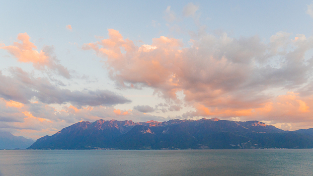 View of Lake Geneva with the Alps in the background under a colorful sunset sky in Bourg en Lavaux Vaud Switzerland. View of Lake Geneva with the Alps in the background under a colorful sunset sky in Bourg en Lavaux Vaud Switzerland.
