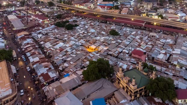 Aerial view of the dense Tamale Central Market featuring rows of corrugated metal rooftops a mosque with a green dome and surrounding urban streets in Tamale Northern Region Ghana. Aerial view of the dense Tamale Central Market featuring rows of corrugated metal rooftops a mosque with a green dome and surrounding urban streets in Tamale Northern Region Ghana.