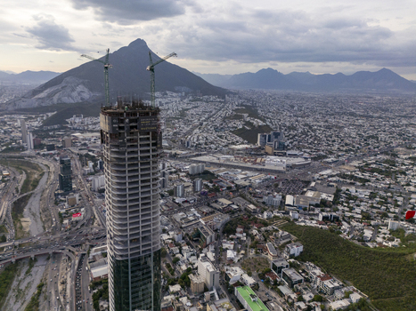 Aerial view of Rise Tower under construction with cranes on top overlooking the urban landscape and surrounding mountains in Monterrey Nuevo Leon Mexico. Aerial view of Rise Tower under construction with cranes on top overlooking the urban landscape and surrounding mountains in Monterrey Nuevo Leon Mexico.