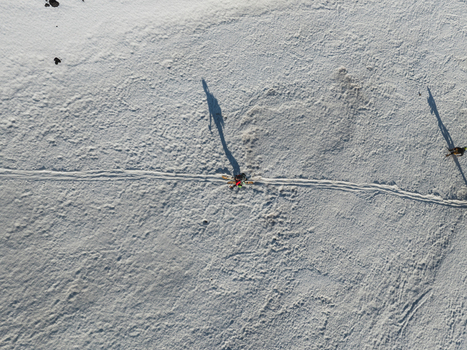 Aerial view of a person walking on the snowy Versante sud dell Etna with long shadows and ski tracks Nicolosi Sicilia Italy. Aerial view of a person walking on the snowy Versante sud dell Etna with long shadows and ski tracks Nicolosi Sicilia Italy.