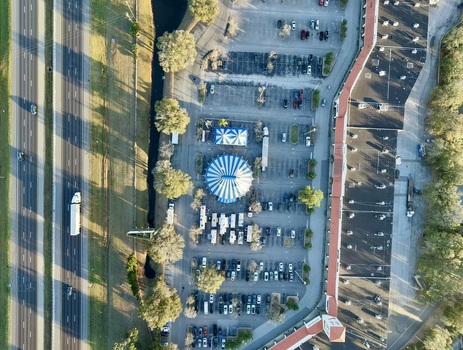 Aerial view of a vibrant blue and white circus tent amidst a sea of parked cars contrasting with the adjacent highway and lush greenery St. Augustine Florida United States. Aerial view of a vibrant blue and white circus tent amidst a sea of parked cars contrasting with the adjacent highway and lush greenery St. Augustine Florida United States.