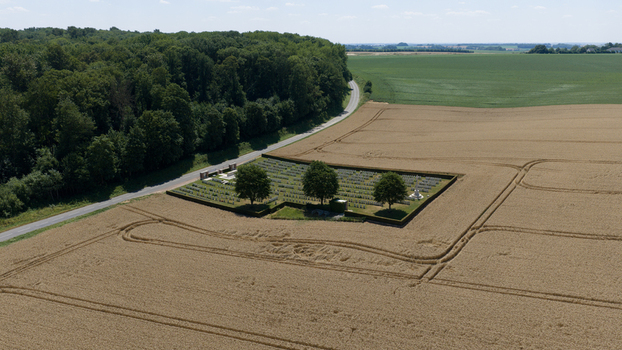 Aerial view of Delville Wood Cemetery surrounded by golden wheat fields and lush forest in Longueval Hauts de France France.
