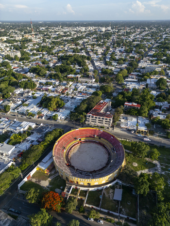 Aerial view of Plaza De Toros Merida with its circular bullring red seating and yellow exterior walls surrounded by the urban landscape of Merida Yucatan Mexico. Aerial view of Plaza De Toros Merida with its circular bullring red seating and yellow exterior walls surrounded by the urban landscape of Merida Yucatan Mexico.
