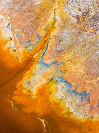 Aerial view of the mineral rich landscape of Rio Tinto with vibrant orange yellow and blue hues cracked earth textures and flowing water patterns in Andalusia Spain. Aerial view of the mineral rich landscape of Rio Tinto with vibrant orange yellow and blue hues cracked earth textures and flowing water patterns in Andalusia Spain.