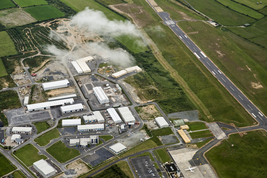 Waterford Regional Airport Ireland 02 July 2015 Aerial view of Waterford Airport featuring the runway industrial hangars and surrounding green fields under a light cloud cover.