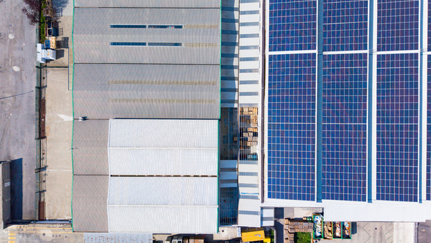 Aerial view of a large industrial distribution center featuring a metal roof and an extensive solar panel array in Milan Lombardy Italy. Aerial view of a large industrial distribution center featuring a metal roof and an extensive solar panel array in Milan Lombardy Italy.