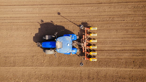 Aerial view of a bright blue tractor with orange implements contrasts against the rich brown earth of a freshly plowed field Sremska Mitrovica Vojvodina Serbia. Aerial view of a bright blue tractor with orange implements contrasts against the rich brown earth of a freshly plowed field Sremska Mitrovica Vojvodina Serbia.