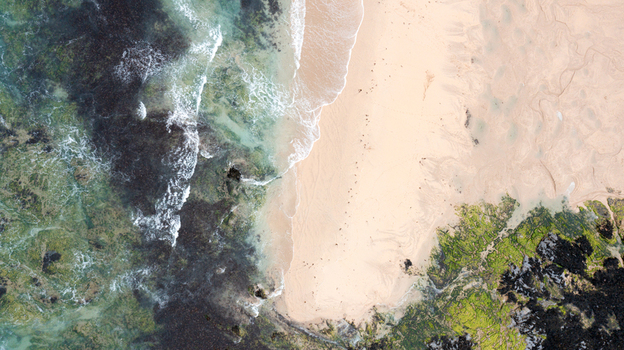 Aerial view of the sandy shore and turquoise waves at Constantine Bay with mossy rocks and clear water in Padstow Cornwall United Kingdom. Aerial view of the sandy shore and turquoise waves at Constantine Bay with mossy rocks and clear water in Padstow Cornwall United Kingdom.