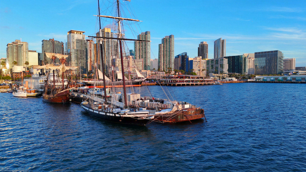 Aerial view of the historic tall ships docked at the North Embarcadero with the modern San Diego skyline in the background under a clear blue sky in San Diego California United States.