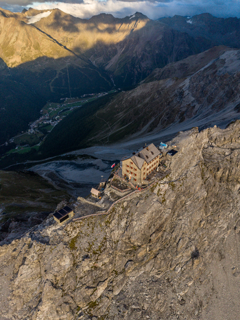 Aerial view of Payer Hutte at Ortler Mountain a historic refuge on a rocky ridge with dramatic alpine peaks steep slopes and a valley village below in Sulden Trentino Alto Adige Italy. Aerial view of Payer Hutte at Ortler Mountain a historic refuge on a rocky ridge with dramatic alpine peaks steep slopes and a valley village below in Sulden Trentino Alto Adige Italy.