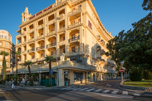 View of the historic Grand Hotel Palace with its yellow facade balconies and palm trees in the coastal town of Opatija Primorje Gorski Kotar Croatia. View of the historic Grand Hotel Palace with its yellow facade balconies and palm trees in the coastal town of Opatija Primorje Gorski Kotar Croatia.