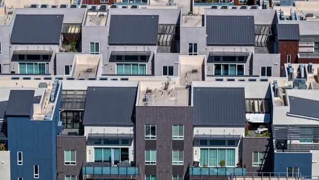 Aerial view of modern residential apartment buildings with dark metal roofs balconies and large windows in a dense urban neighborhood in Fremont California United States.