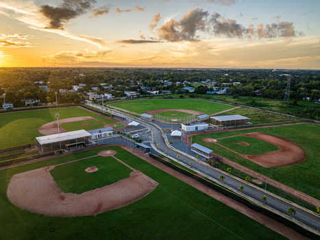Aerial view of Quality Baseball Academy featuring baseball diamonds green fields and palm trees at sunset in San Antonio de Guerra Santo Domingo Provinc Dominican Republic. Aerial view of Quality Baseball Academy featuring baseball diamonds green fields and palm trees at sunset in San Antonio de Guerra Santo Domingo Provinc Dominican Republic.
