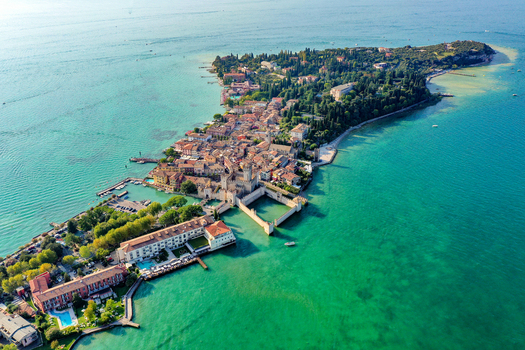 Aerial view of Castello Scaligero di Sirmione and the historic peninsula surrounded by the turquoise waters of Lake Garda in Sirmione Lombardia Italy.
