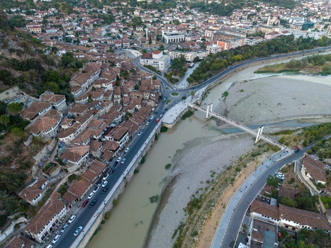 Aerial view of the historic city of Berat featuring traditional Ottoman style houses with terracotta roofs the Osum River and a pedestrian bridge in Berat Berat County Albania.