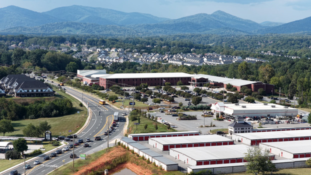 Aerial view of a school complex with parking lots a road with traffic and surrounding residential neighborhoods nestled against distant mountains in Forest Virginia United States.