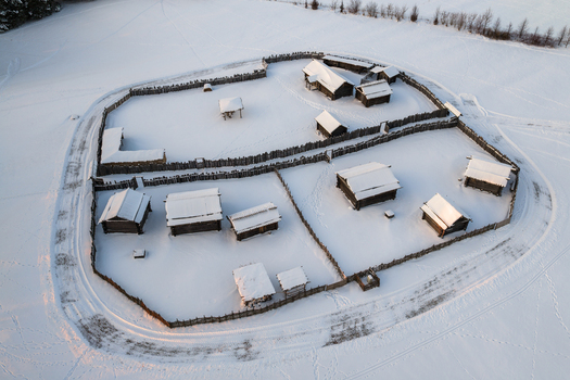 Aerial view of the reconstructed wooden settlement at Kernave Archaeological Site with snow covered rooftops and wooden fences during winter Kernave Vilnius County Lithuania.
