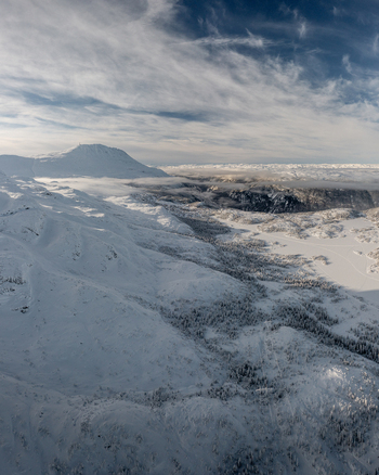 Aerial view of the snowy Gaustablikk Fjellresort area in the mountains featuring vast snow covered slopes frozen lakes and wispy clouds in Rjukan Telemark Norway. Aerial view of the snowy Gaustablikk Fjellresort area in the mountains featuring vast snow covered slopes frozen lakes and wispy clouds in Rjukan Telemark Norway.