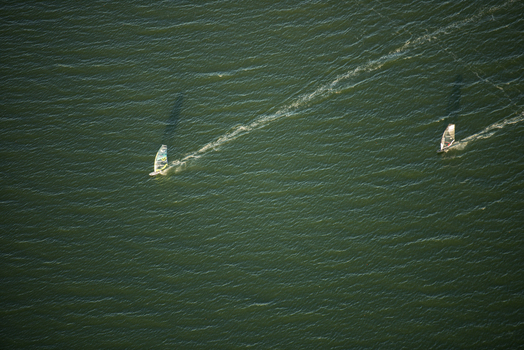 Aerial view of two windsurfers gliding across the deep green waters of Guanabara Bay in Rio de Janeiro Rio de Janeiro Brazil. Aerial view of two windsurfers gliding across the deep green waters of Guanabara Bay in Rio de Janeiro Rio de Janeiro Brazil.