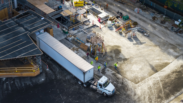 Aerial view of construction activity at Kendall Square with a semi truck and workers in high visibility vests near scaffolding in Cambridge Massachusetts United States. Aerial view of construction activity at Kendall Square with a semi truck and workers in high visibility vests near scaffolding in Cambridge Massachusetts United States.