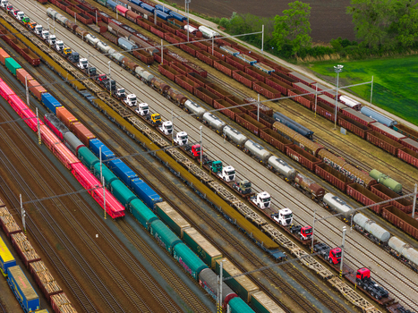 Aerial view of a busy railway yard with freight trains including flatbed rail cars loaded with semi trucks cargo containers and tankers in Breclav South Moravian Region Czechia.