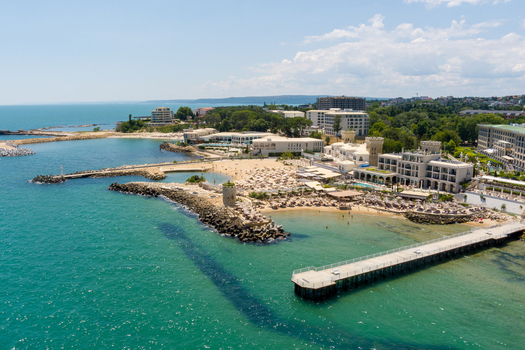 Aerial view of Saints Constantine and Helena resort with sandy beach long pier turquoise Black Sea and hotel architecture in Saints Constantine and Helena Varna Bulgaria.