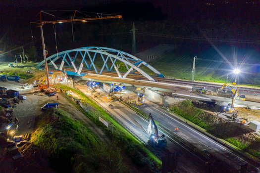 Forchheim Germany 18 May 2024 Aerial view of the A73 highway bridge construction site at night with a large crane excavators and bright floodlights illuminating the works. Forchheim Germany 18 May 2024 Aerial view of the A73 highway bridge construction site at night with a large crane excavators and bright floodlights illuminating the works.